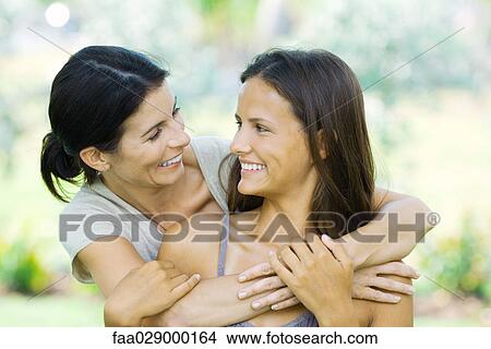 Picture - Mother and teen daughter embracing, smiling at each other. Fotosearch