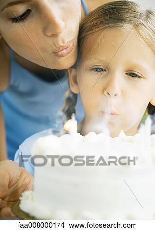 Mother helping daughter blow out birthday candles View Large Photo Image Picture - Mother helping daughter blow out birthday candles. Fotosearch