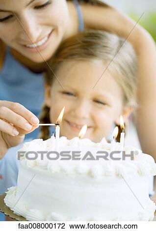 Mother lighting candles on birthday cake for daughter View Large Photo Image Stock Image - Mother lighting candles on birthday cake for daughter. Fotosearch