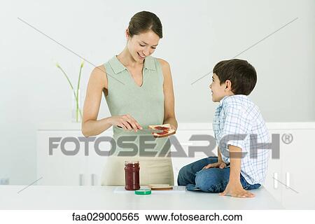Mother spreading jam on bread, chatting with young son View Large Photo Image Stock Photography - Mother spreading jam on bread, chatting with young son. Fotosearch