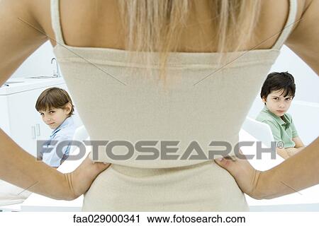 Mother standing with hands on hips, rear view, boys sulking in background, cropped view View Large Photo Image Stock Image - Mother standing with hands on hips, rear view, boys sulking in background, cropped view. Fotosearch