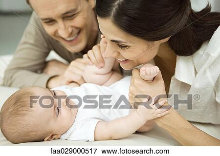 New parents smiling at infant, mother holding baby's legs, close-up View Large Photo Image Stock Photo - New parents smiling at infant, mother holding baby's legs, close-up. Fotosearch