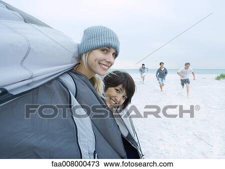 On beach, two young women sticking heads out of tent while friends run toward them in distance View Large Photo Image Stock Image - On beach, two young women sticking heads out of tent while friends run toward them in distance. Fotosearch