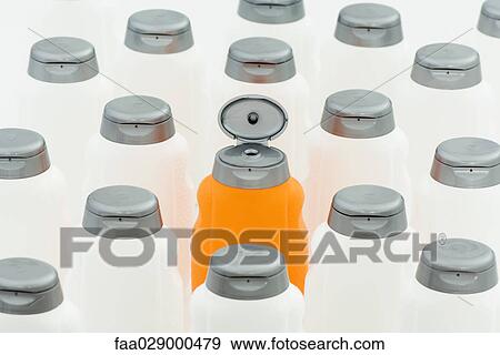 Stock Photo - Open orange bottle among group of closed white bottles. Fotosearch