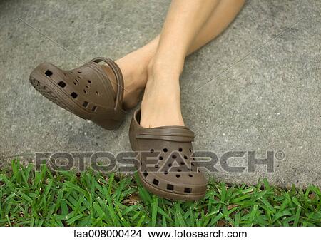 Person crossing legs at ankles, wearing gardening shoes View Large Photo Image Picture - Person crossing legs at ankles, wearing gardening shoes. Fotosearch