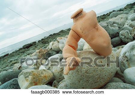 Plastic doll part on rocks pebbly beach View Large Photo Image Stock Photography - Plastic doll part on rocks pebbly beach. Fotosearch
