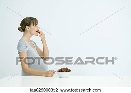 Pregnant woman eating bowl of strawberries, side view View Large Photo Image Stock Image - Pregnant woman eating bowl of strawberries, side view. Fotosearch