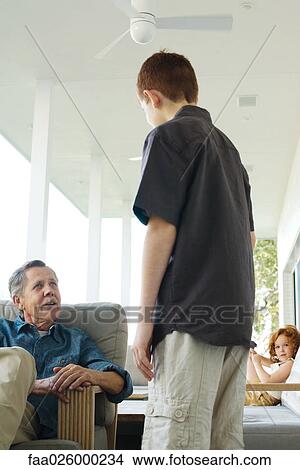 Preteen boy standing face to face with grandfather on porch, little girl sitting in background View Large Photo Image Picture - Preteen boy standing face to face with grandfather on porch, little girl sitting in background. Fotosearch