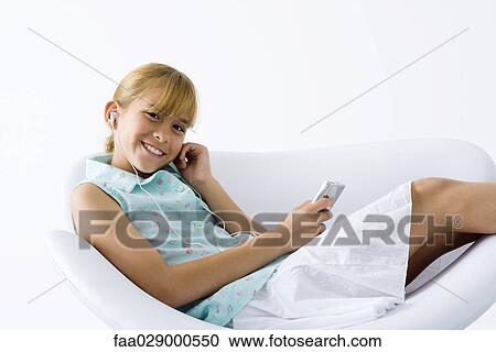 Preteen girl sitting in chair, listening to MP3 player, smiling at camera View Large Photo Image Stock Image - Preteen girl sitting in chair, listening to MP3 player, smiling at camera. Fotosearch