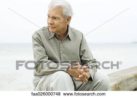Senior man sitting near sea, looking away View Large Photo Image Stock Photo - Senior man sitting near sea, looking away. Fotosearch