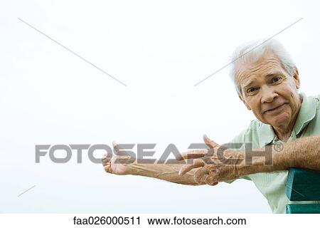 Stock Image - Senior man with arms out, furrowing brow, looking at camera. Fotosearch