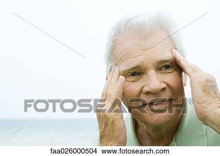 Picture - Senior man with fingers at side of head, smiling, looking away. Fotosearch