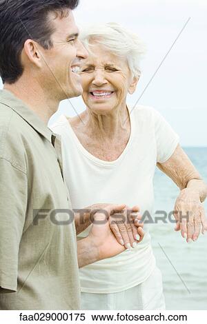 Senior woman and adult son holding hands, laughing, eyes closed View Large Photo Image Stock Photography - Senior woman and adult son holding hands, laughing, eyes closed. Fotosearch