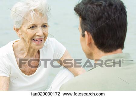 Senior woman sitting across from man, smiling View Large Photo Image Stock Image - Senior woman sitting across from man, smiling. Fotosearch