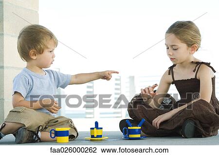 Siblings sitting on the ground together, brother pointing a sister, sister looking down at finger View Large Photo Image Stock Image - Siblings sitting on the ground together, brother pointing a sister, sister looking down at finger. Fotosearch