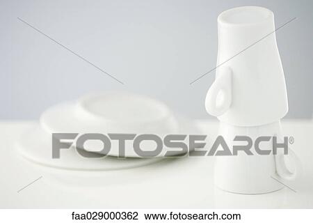 Stock Image - Stacked coffee mugs and saucers, close-up. Fotosearch