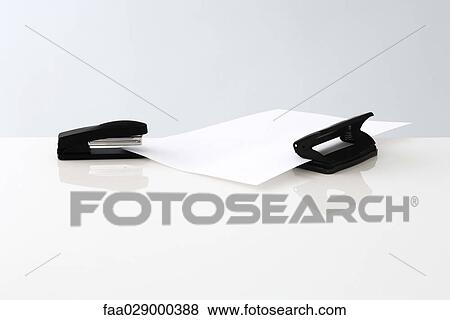 Stock Photo - Stapler and hole puncher with single sheet of paper. Fotosearch