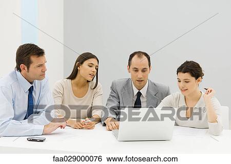 Team of business associates looking at laptop computer together in office View Large Photo Image Stock Photograph - Team of business associates looking at laptop computer together in office. Fotosearch