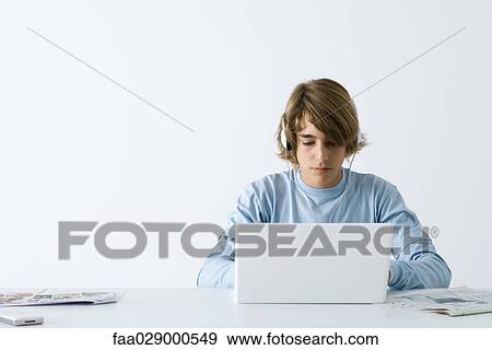 Teen boy using laptop computer, listening to headphones View Large Photo Image Stock Photo - Teen boy using laptop computer, listening to headphones. Fotosearch