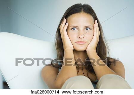 Teen girl sitting with knees up, holding head in hands, looking away View Large Photo Image Picture - Teen girl sitting with knees up, holding head in hands, looking away. Fotosearch