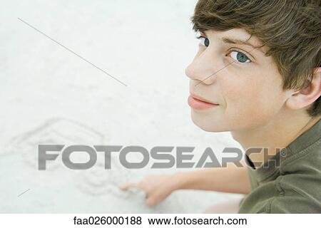 Stock Photo - Teenage boy drawing car in sand, cropped view. Fotosearch