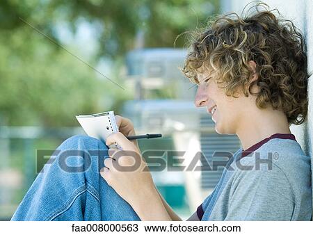 Teenage boy sitting with pen and notebook, side view View Large Photo Image Stock Image - Teenage boy sitting with pen and notebook, side view. Fotosearch