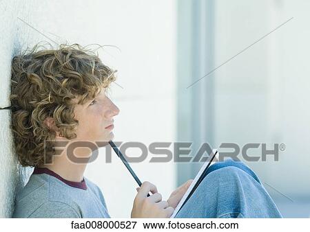Teenage boy sitting with pen and notebook, side view View Large Photo Image Stock Photo - Teenage boy sitting with pen and notebook, side view. Fotosearch