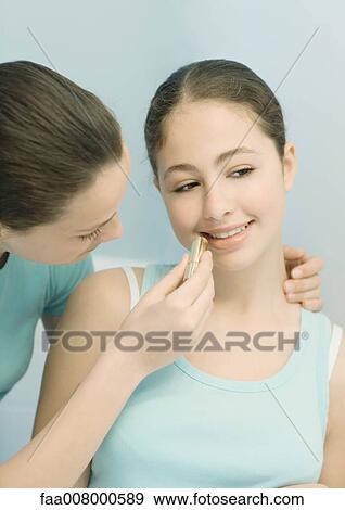 Teenage girl putting lipstick on friend View Large Photo Image Stock Photo - Teenage girl putting lipstick on friend. Fotosearch