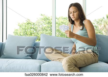 Teenage girl sitting on couch, looking down at cards in hand View Large Photo Image Stock Image - Teenage girl sitting on couch, looking down at cards in hand. Fotosearch