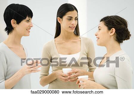 Three women chatting together, all holding disposable coffee cups View Large Photo Image Stock Image - Three women chatting together, all holding disposable coffee cups. Fotosearch