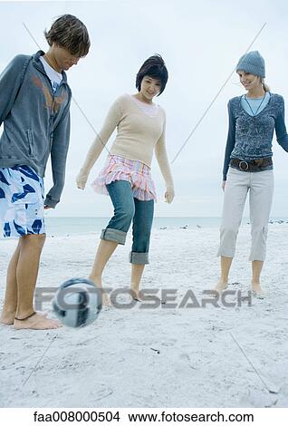 Three young adult friends playing soccer on beach View Large Photo Image Picture - Three young adult friends playing soccer on beach. Fotosearch