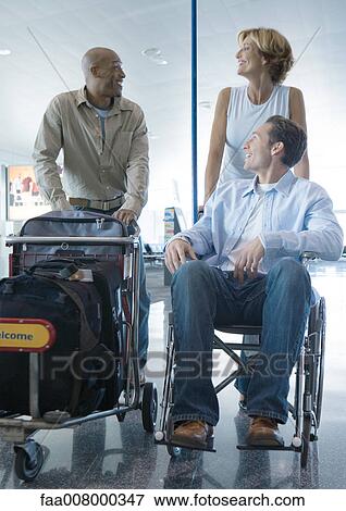 Travelers in airport, one in wheelchair View Large Photo Image Stock Photo - Travelers in airport, one in wheelchair. Fotosearch