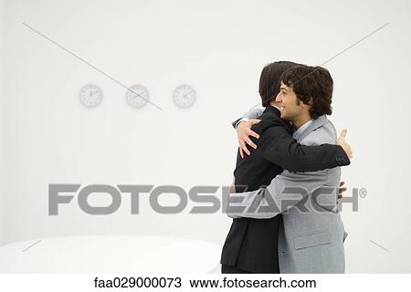 Two businessmen embracing, smiling, side view View Large Photo Image Stock Image - Two businessmen embracing, smiling, side view. Fotosearch