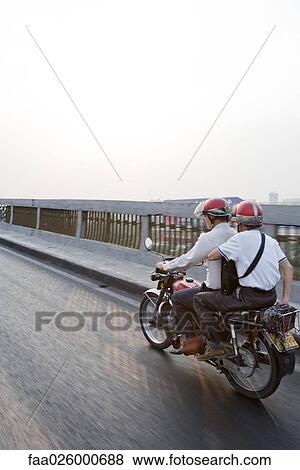 Two commuters riding motorbike together View Large Photo Image Stock Photo - Two commuters riding motorbike together. Fotosearch