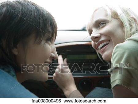 Stock Photograph - Two female friends in car, one tuning radio. Fotosearch