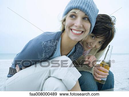 Two female friends on beach, one with bottle of beer View Large Photo Image Stock Photo - Two female friends on beach, one with bottle of beer. Fotosearch