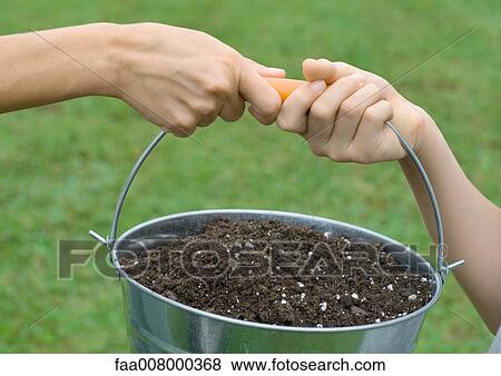 Two people's hands holding pot of soil together, close-up View Large Photo Image Stock Photo - Two people's hands holding pot of soil together, close-up. Fotosearch