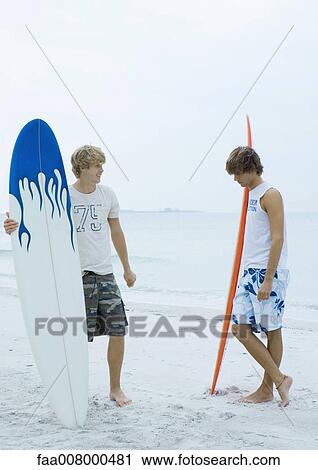 Two surfers standing on beach View Large Photo Image Stock Image - Two surfers standing on beach. Fotosearch
