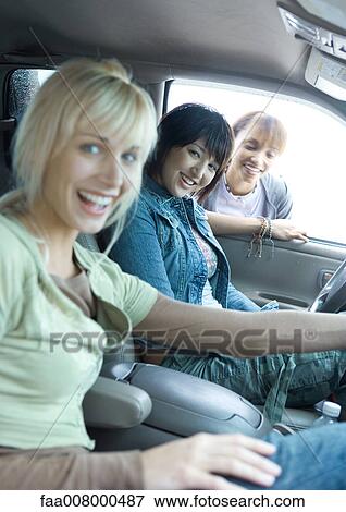 Two women sitting in car, third women looking through car window View Large Photo Image Stock Photo - Two women sitting in car, third women looking through car window. Fotosearch