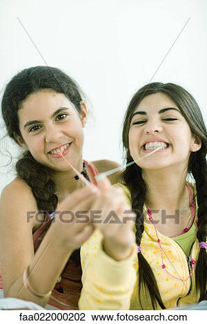 Two young female friends pulling chewing gum out of their mouths, portrait View Large Photo Image Stock Image - Two young female friends pulling chewing gum out of their mouths, portrait. Fotosearch