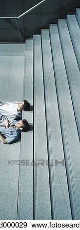 Stock Photo - Two young men lying with heads on steps. Fotosearch