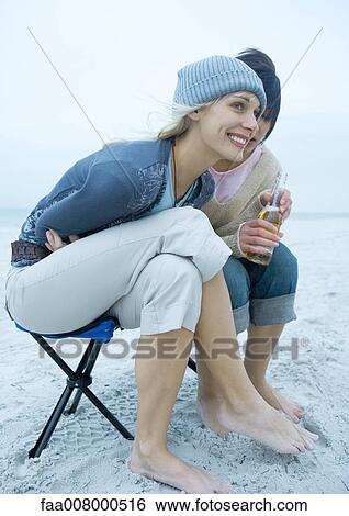 Two young women on beach, leaning forward, on holding beer bottle View Large Photo Image Stock Photograph - Two young women on beach, leaning forward, on holding beer bottle. Fotosearch