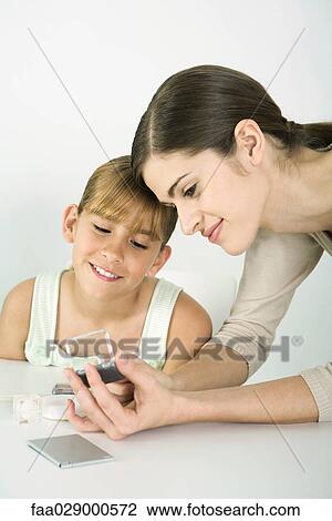 Woman and girl looking at make-up together, both smiling View Large Photo Image Stock Image - Woman and girl looking at make-up together, both smiling. Fotosearch