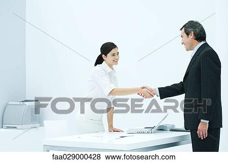 Woman and man shaking hands in office View Large Photo Image Stock Photo - Woman and man shaking hands in office. Fotosearch