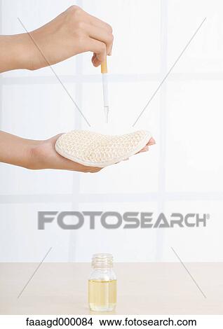 Woman dropping essential oil onto sponge View Large Photo Image Picture - Woman dropping essential oil onto sponge. Fotosearch