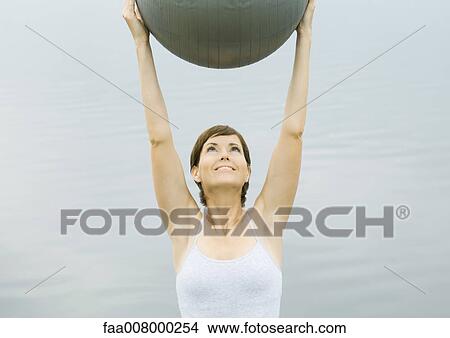 Woman exercising with fitness ball, next to lake View Large Photo Image Picture - Woman exercising with fitness ball, next to lake. Fotosearch