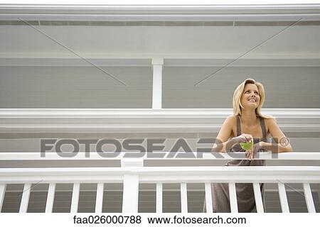 Woman holding apple, leaning over deck railing, low angle view View Large Photo Image Stock Photo - Woman holding apple, leaning over deck railing, low angle view. Fotosearch