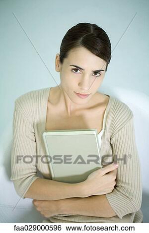 Woman holding book, looking at camera, portrait View Large Photo Image Stock Photograph - Woman holding book, looking at camera, portrait. Fotosearch