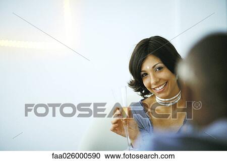 Woman holding champagne glass, smiling at camera, man in foreground View Large Photo Image Stock Image - Woman holding champagne glass, smiling at camera, man in foreground. Fotosearch