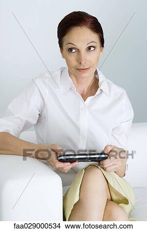 Woman holding handheld video game, looking up View Large Photo Image Picture - Woman holding handheld video game, looking up. Fotosearch